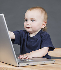 Image showing baby with laptop computer in grey background