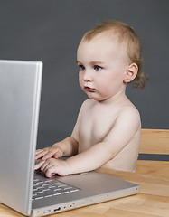 Image showing baby with laptop computer in grey background