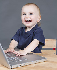 Image showing baby with laptop computer in grey background