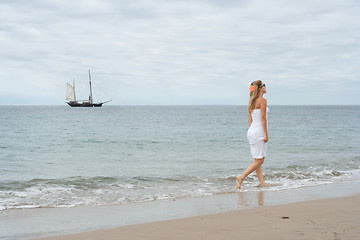 Image showing Girl in white dress on the coast with old ship in the background