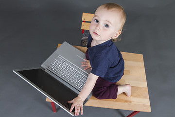 Image showing baby with laptop computer in grey background