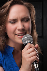 Image showing Girl singing to the microphone in a studio