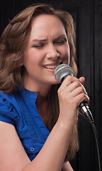 Image showing Girl singing to the microphone in a studio