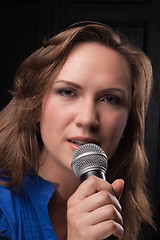 Image showing Girl singing to the microphone in a studio