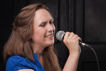 Image showing Girl singing to the microphone in a studio