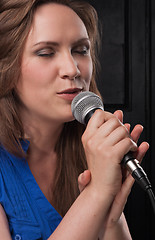 Image showing Girl singing to the microphone in a studio