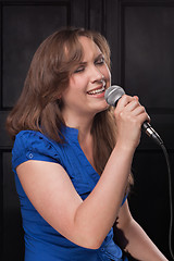 Image showing Girl singing to the microphone in a studio