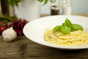 Image showing tasty fresh pasta with garlic and basil on table