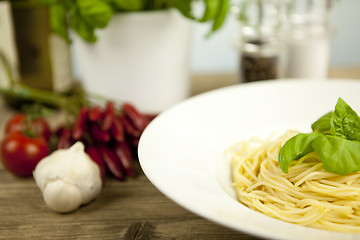 Image showing tasty fresh pasta with garlic and basil on table