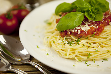 Image showing delicious fresh spaghetti with tomato sauce and parmesan on table