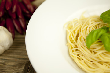 Image showing tasty fresh pasta with garlic and basil on table
