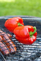 Image showing Red sweet pepper and sausages on a grill