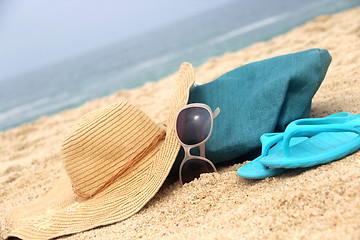 Image showing Blue beach bag on the seacoast and straw hat 