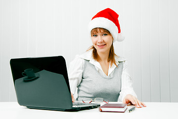 Image showing girl in a Christmas hat with a laptop