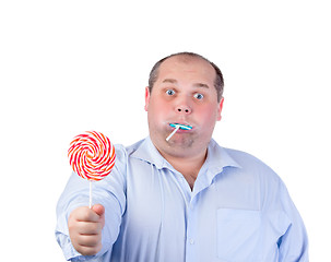 Image showing Fat Man in a Blue Shirt, Eating a Lollipop