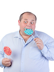 Image showing Fat Man in a Blue Shirt, Eating a Lollipop