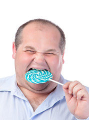 Image showing Fat Man in a Blue Shirt, Eating a Lollipop