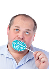 Image showing Fat Man in a Blue Shirt, Eating a Lollipop