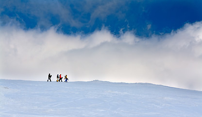 Image showing Four snowboarders go up the hill