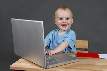 Image showing baby with laptop computer in grey background