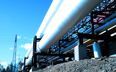 Image showing industrial pipelines with insulation against natural blue backgr