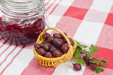 Image showing Basket with berries of a red gooseberry and jam