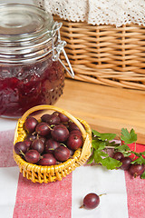 Image showing Basket with berries of a red gooseberry and jam