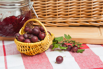 Image showing Basket with berries of a red gooseberry and jam