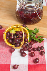 Image showing Basket with berries of a red gooseberry and jam