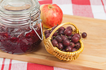 Image showing Basket with berries of a red gooseberry and jam