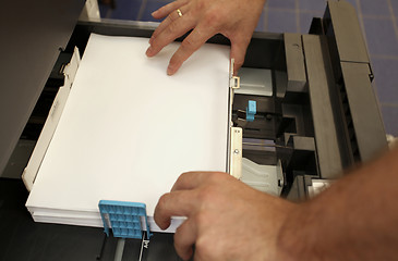 Image showing details of hand inserts a paper A4 into a laser copier 