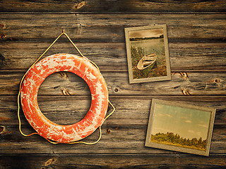 Image showing lifebuoy and old travel photos at wooden background