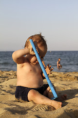 Image showing Baby playing with toy on a sandy beach