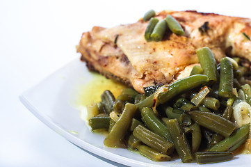 Image showing Fried chicken leg with french beans on white plate.