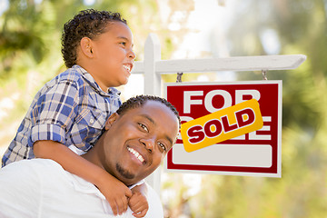 Image showing Mixed Race Father and Son In Front of Sold Real Estate Sign