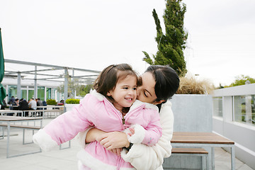 Image showing Happy little girl receiving a kiss of her mother