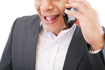 Image showing  angry young male executive yelling on his mobile phone against 