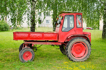 Image showing Retro red agricultural tractor under birch trees 