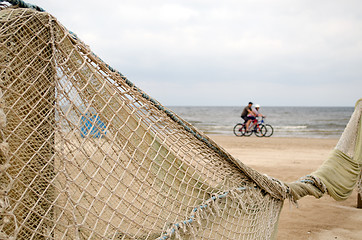 Image showing Beach fence decorated net cyclists going near sea 