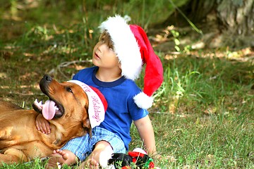 Image showing Little boy wiith dog both wearing Santa hats