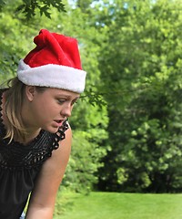 Image showing Young woman wearing a Santa Hat with trees in  background