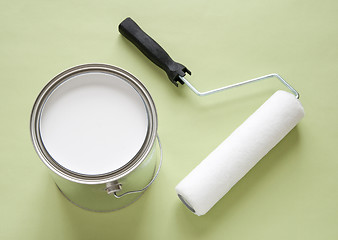 Image showing Can of white paint and roller on green background