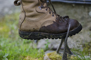 Image showing A leather walking boot, being cleaned on an old cast iron boot s