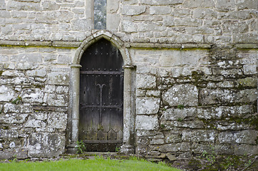 Image showing An old wooden door, in the stone wall of an old 14th Century chu