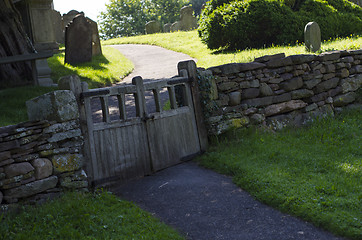 Image showing Old wooden double gate in dry stone wall to churchyard