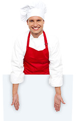 Image showing A smiling chef posing behind white billboard