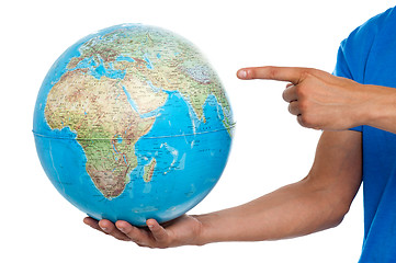 Image showing A finger pointing at the globe. closeup shot