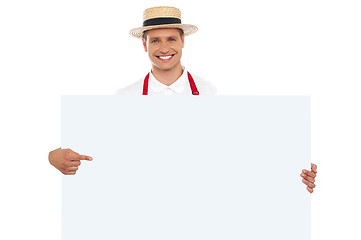 Image showing Portrait of cheerful chef pointing at placard