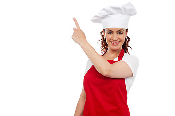 Image showing Attractive female chef pointing at copy space