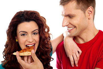 Image showing Girl enjoying pizza piece shared by her boyfriend